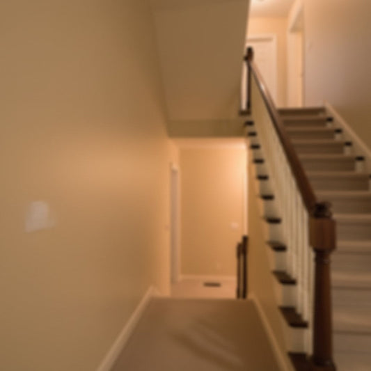A blurred view looking up a residential wooden staircase and hallway bathed in warm ambient light. The composition features significant open space on the left against neutral beige walls.