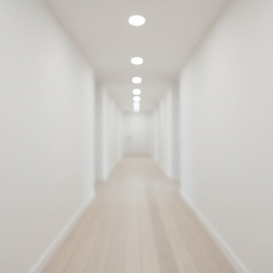 A blurred perspective looks down a clean white hallway featuring light wood flooring and neutral white recessed ceiling lights.